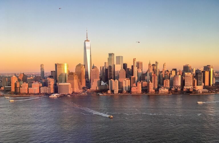 Downtown Manhattan skyline and One World Trade Center at golden hour across the Hudson River