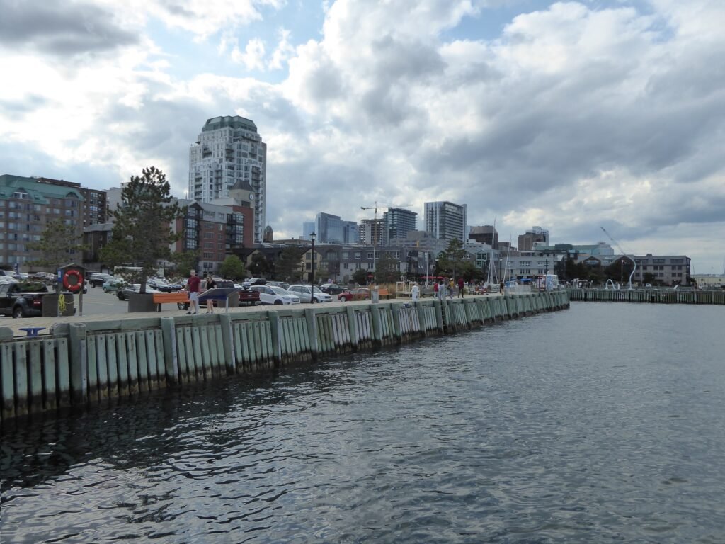 Pedestrians along the Halifax waterfront promenade with downtown buildings beyond