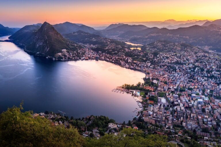 Lake Lugano and Lugano at sunset with surrounding mountains