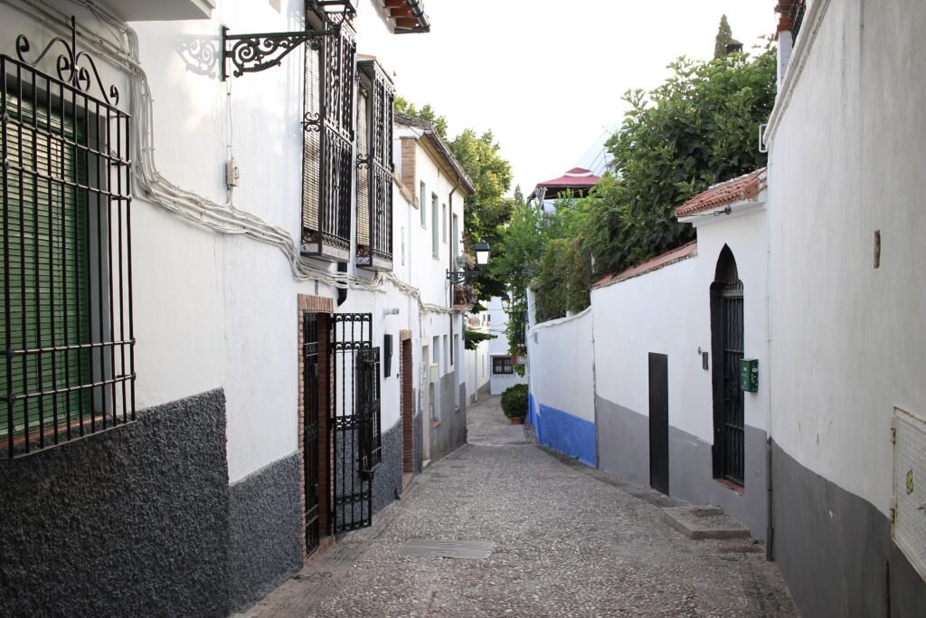 A sloping narrow street lined with white houses in Granada's Albaicín