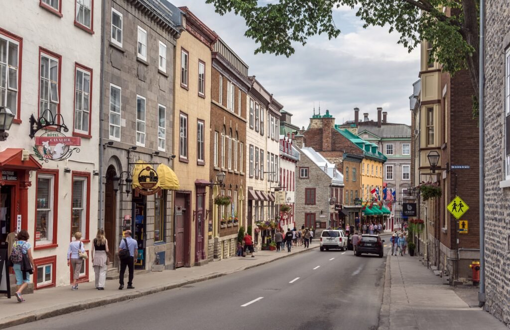 Pedestrians on a downhill street lined with historic buildings in Old Quebec