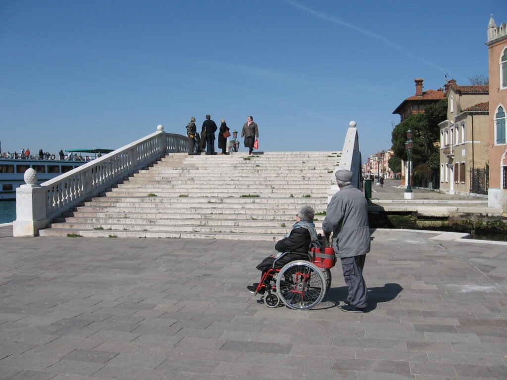 Stepped footbridge over a Venice canal with a wheelchair user beside the bridge