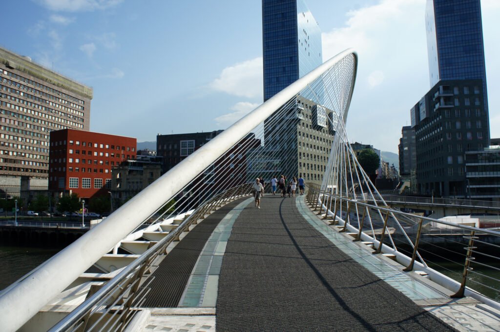 Pedestrians crossing the white Zubizuri bridge in central Bilbao