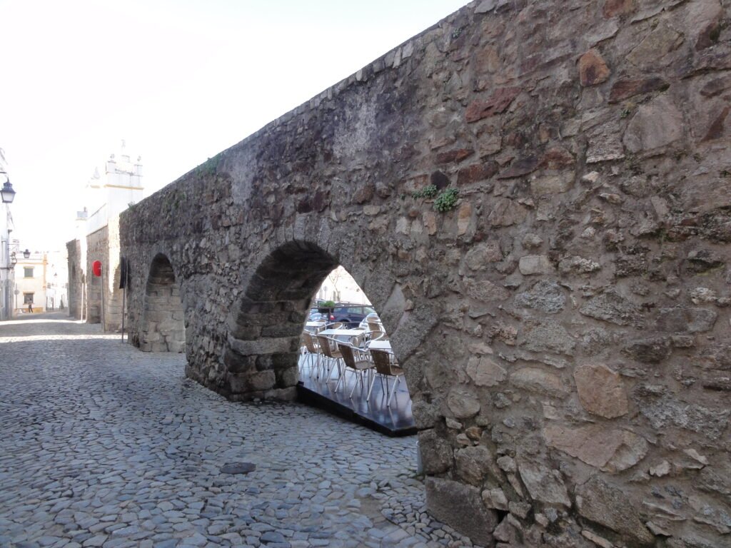 Aqueduto da Água de Prata crossing Rua do Cano in Évora beside cobbled paving