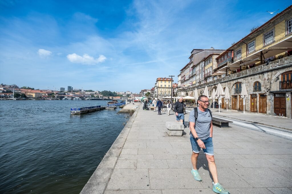 Pedestrians walking along the Cais da Ribeira promenade beside the Douro River in Porto