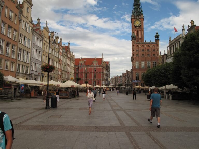 Pedestrians walking across Długi Targ beside Gdańsk Main Town Hall