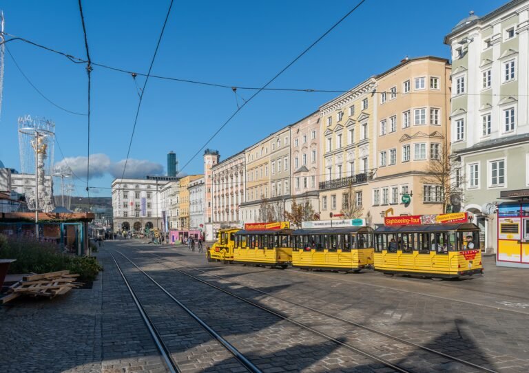 Pedestrians crossing Hauptplatz in central Linz among historic buildings
