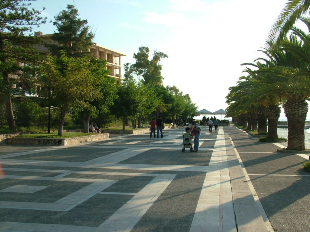 Pedestrians walking along the broad seafront promenade in Nafplio