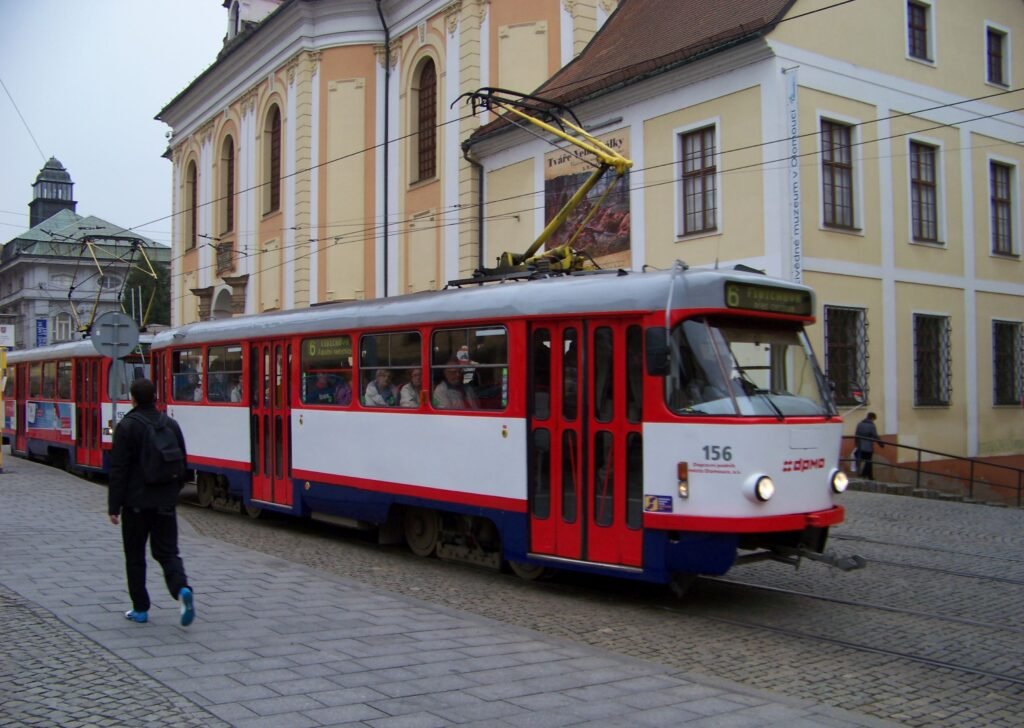Tram passing Náměstí Republiky in Olomouc beside pedestrian paving and museum buildings