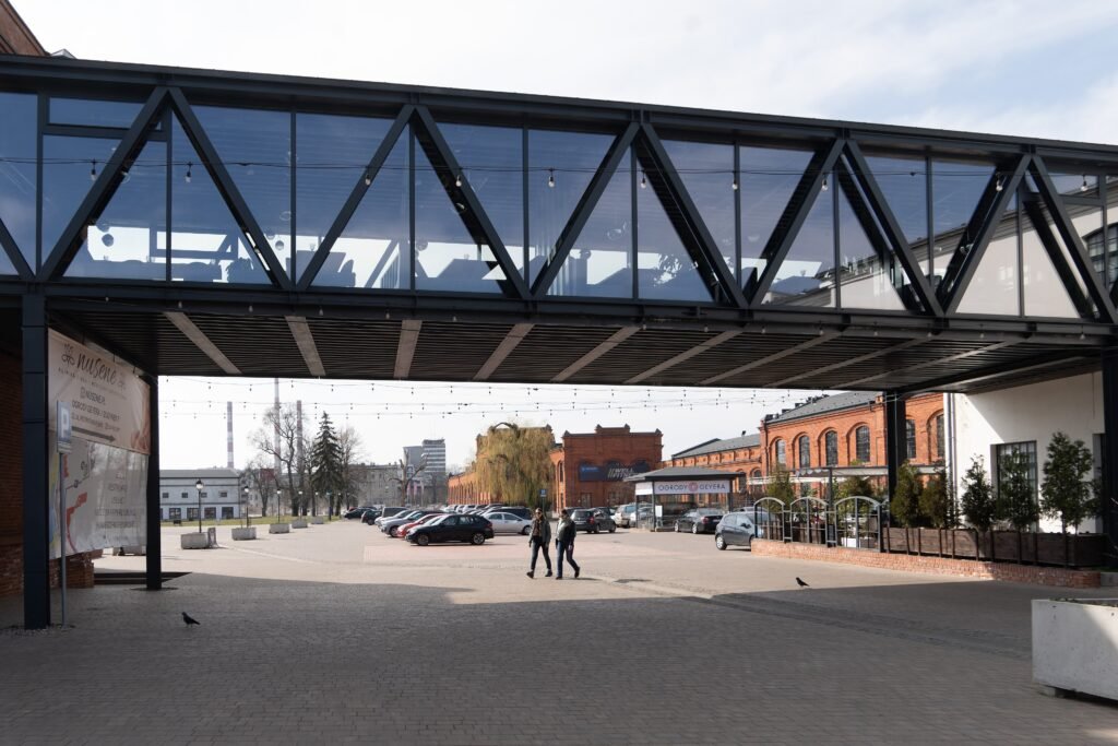Industrial courtyard entrance at OFF Piotrkowska in Łódź with pedestrians and parked cars