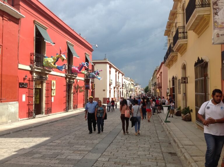 Pedestrians walking along a colorful pedestrian street in central Oaxaca City