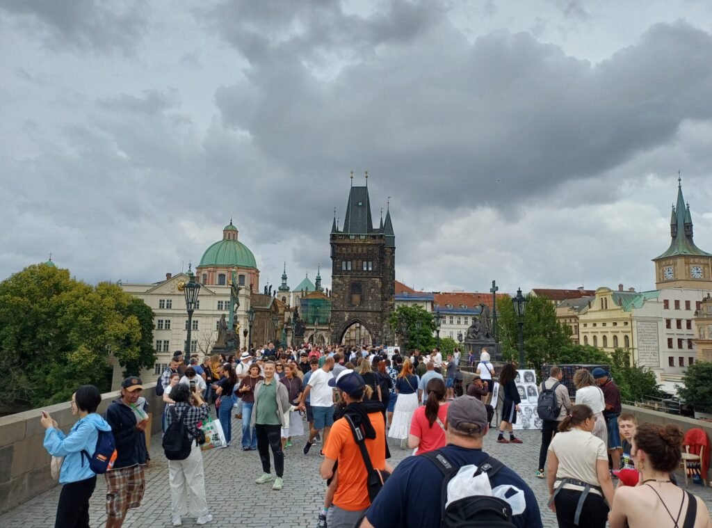 Pedestrians walking across crowded Charles Bridge in Prague