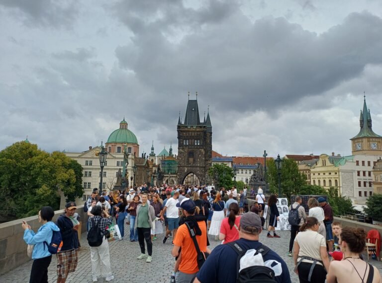 Pedestrians walking across crowded Charles Bridge in Prague