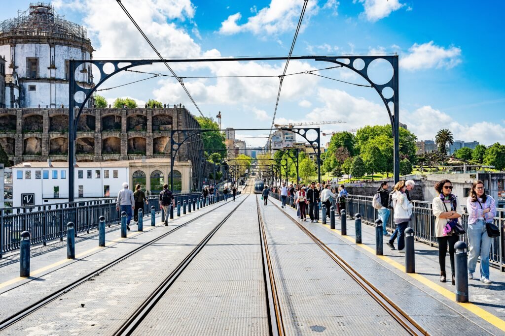 Pedestrians walking on the upper deck of Dom Luís I Bridge beside Porto Metro tracks