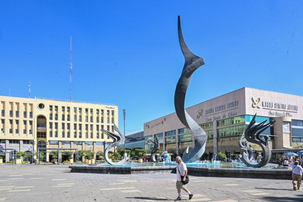 Pedestrian crossing Plaza Tapatía with public art and Mercado San Juan de Dios behind