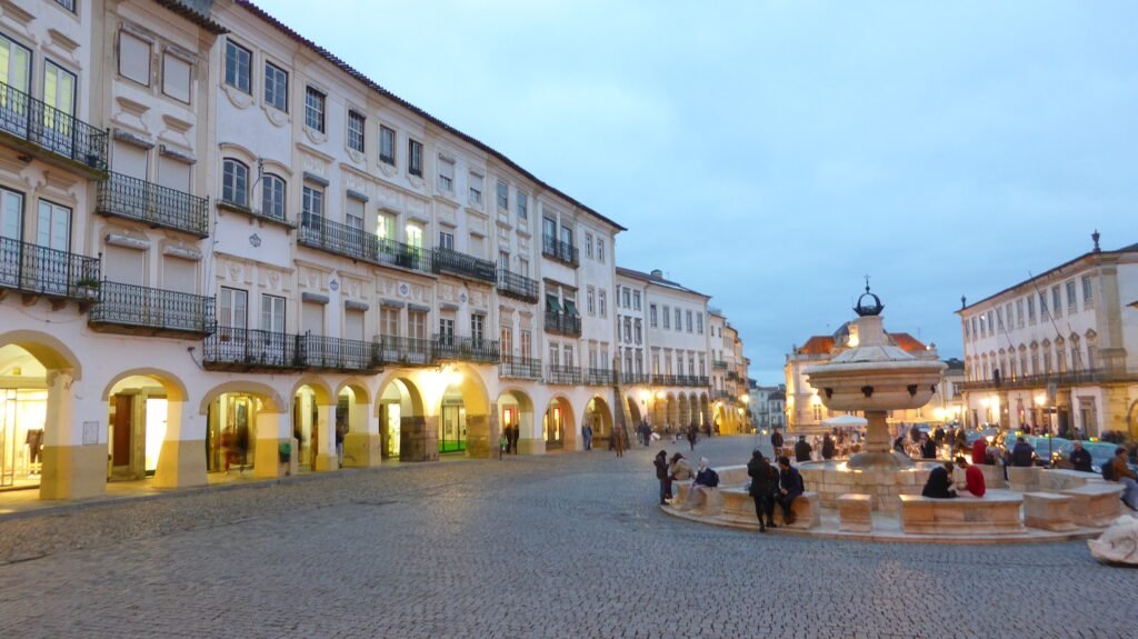 Praça do Giraldo in Évora with arcades, fountain and pedestrians on stone paving
