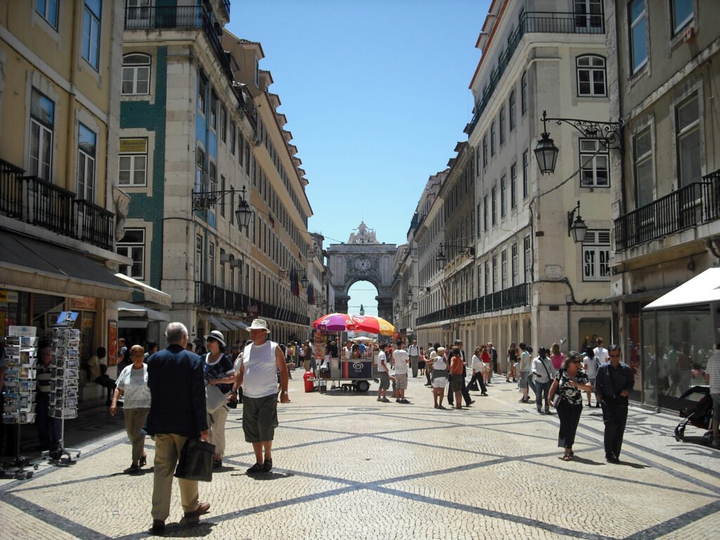 Pedestrians walking on Rua Augusta over patterned Portuguese calçada in central Lisbon