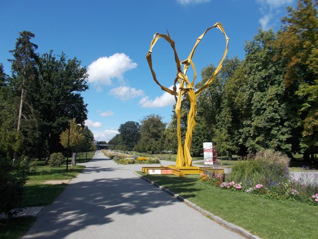 Wide paved promenade through Smetanovy sady in Olomouc with trees and flower beds