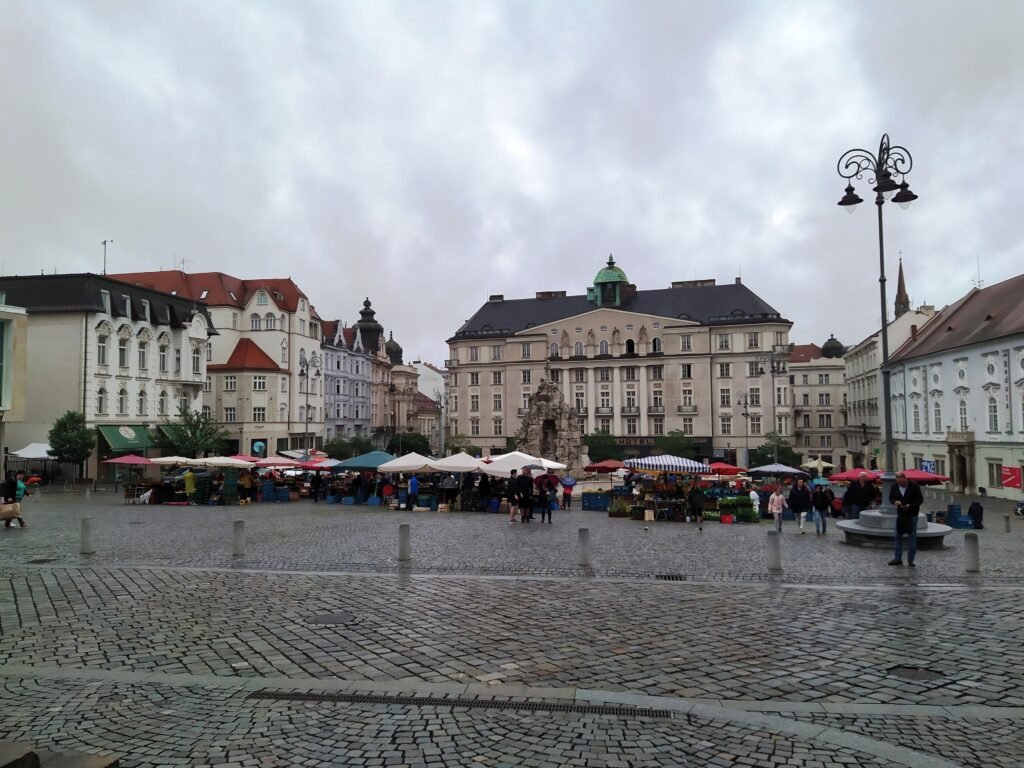Pedestrians and market activity on the cobbled Zelný trh in Brno